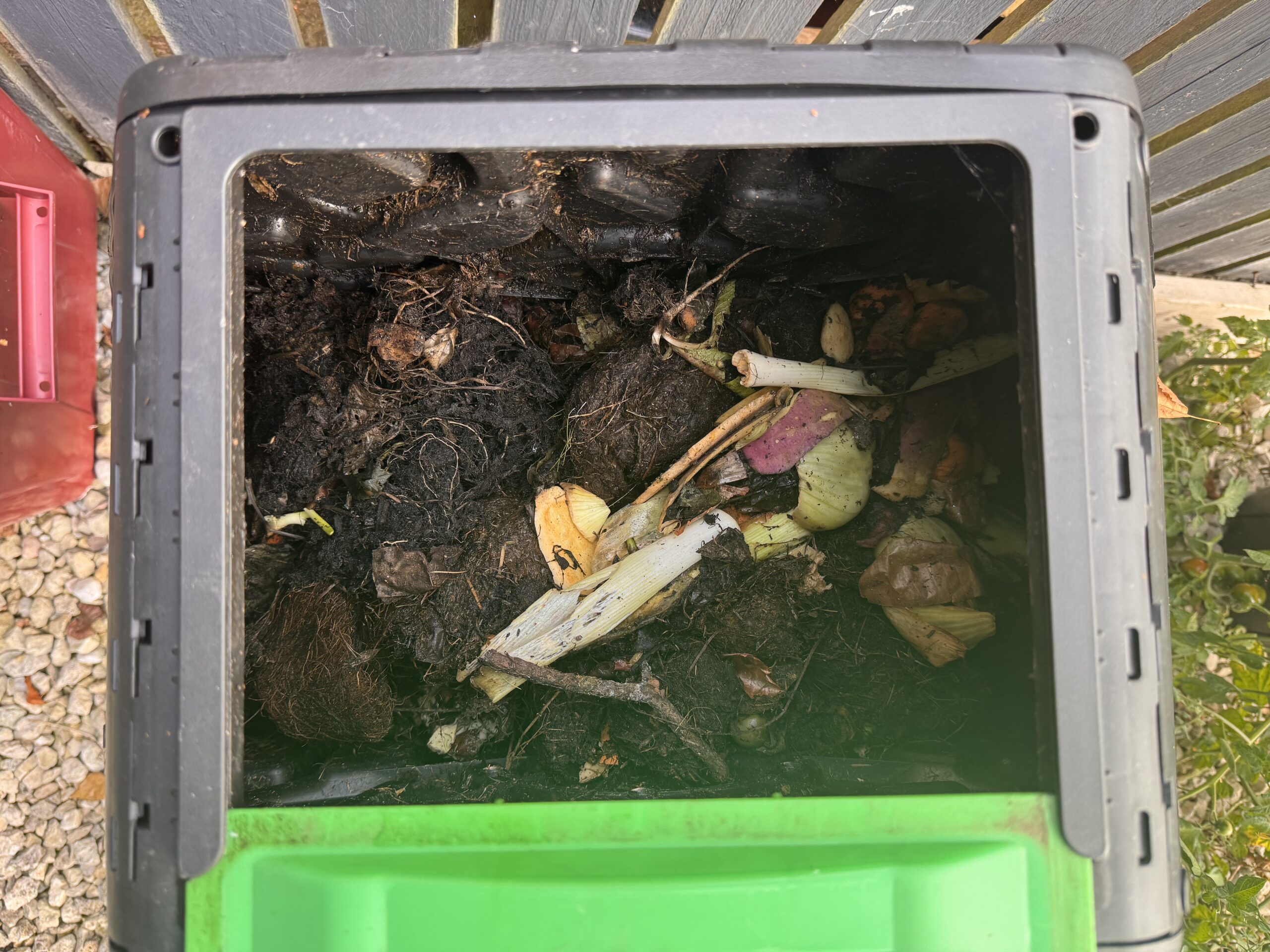 Fresh vegetable peelings alongside darker decomposing material inside the Outsunny compost bin
