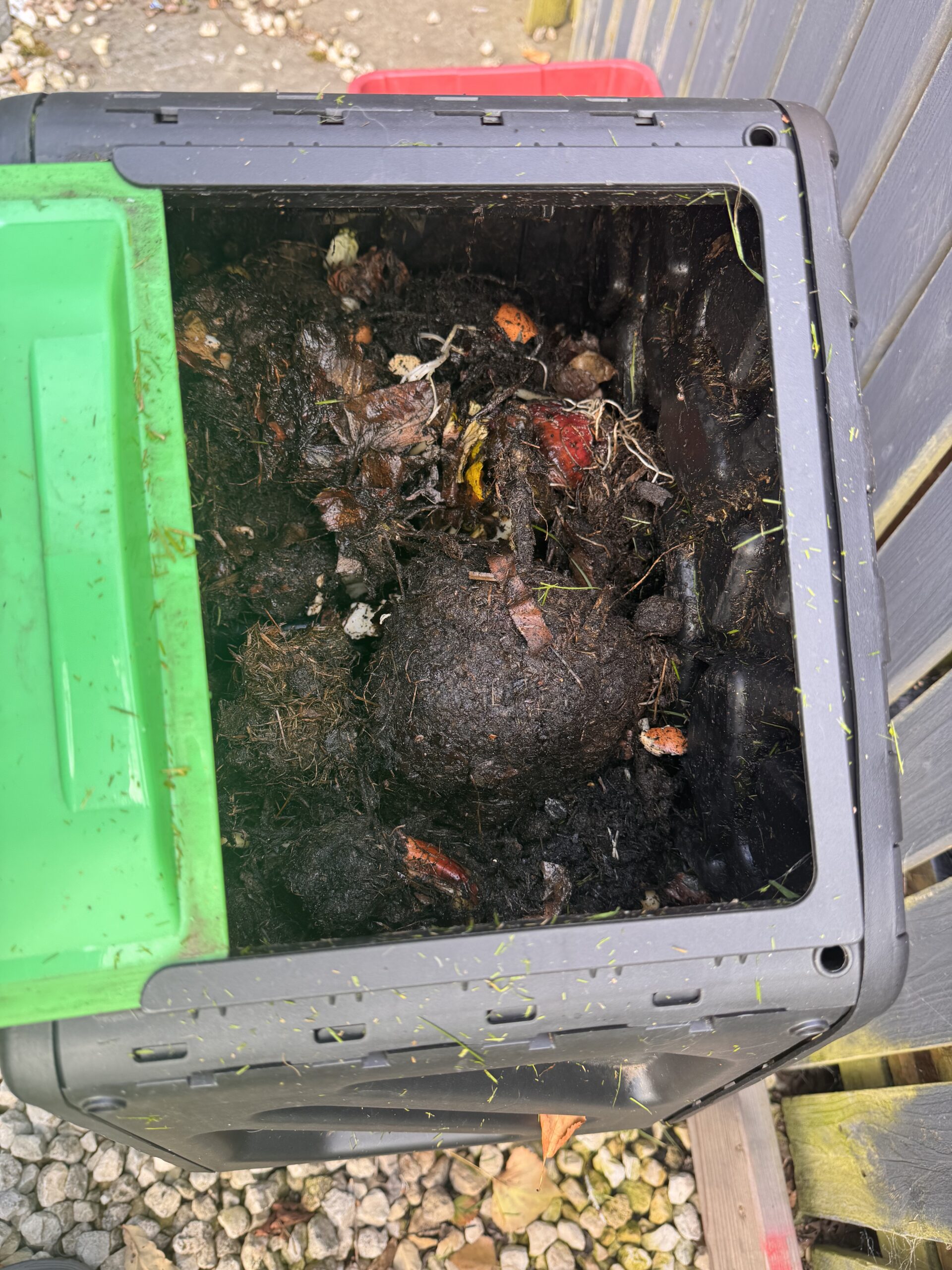 Dark decomposing garden waste with recognisable leaves and vegetable scraps in the Outsunny tumbler